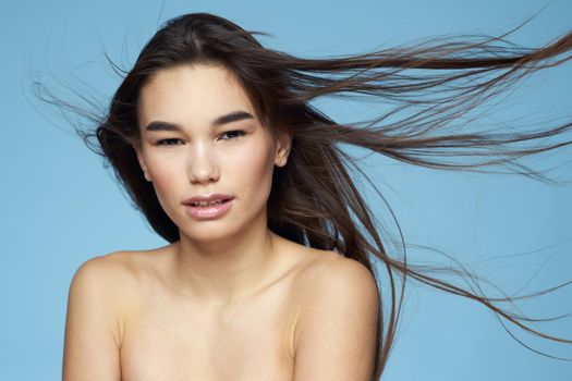 pretty brunette naked shoulders long hair skin care blue background. High quality photo