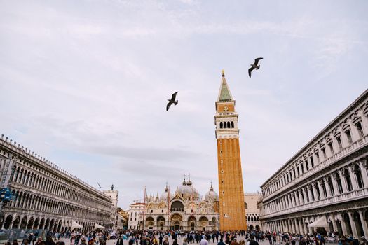A huge bell tower made of red brick in Piazza San Marco in Venice, Italy. Against background of a cloudy, evening, October sunset sky.