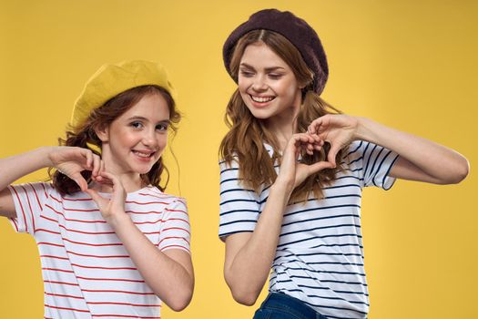 funny mom and daughter wearing hats fashion fun joy family yellow background. High quality photo