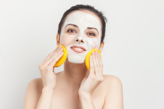 cheerful brunette with bare shoulders face mask sponges in hands skin care. High quality photo