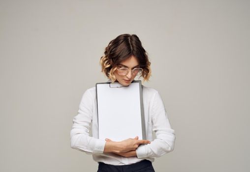 Folder with a white sheet of paper on a gray background in the hands of a woman mockup. High quality photo