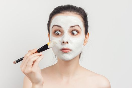 brunette naked shoulders face cream brush in hand. High quality photo