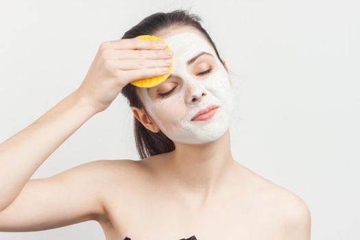 brunette naked shoulders face cream brush in hand. High quality photo