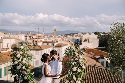 Interracial wedding couple. Destination fine-art wedding in Florence, Italy. A wedding ceremony on the roof of the building, with cityscape views of the city and Cathedral of Santa Maria Del Fiore