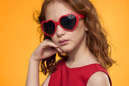 Girl in black glasses red dress childhood fun yellow background. High quality photo