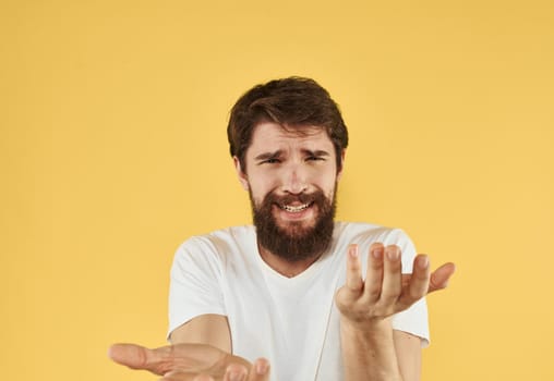 Emotional guy in a white t-shirt on a yellow background gesturing with his hands cropped view. High quality photo
