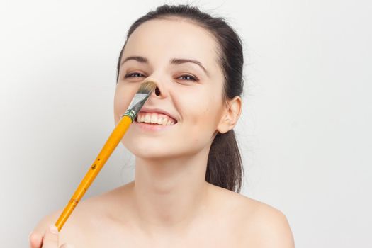 brunette naked shoulders face cream brush in hand. High quality photo