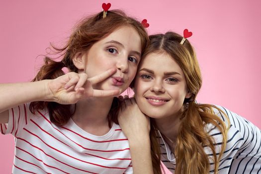 cheerful girl and woman on a pink background sisters family emotions. High quality photo