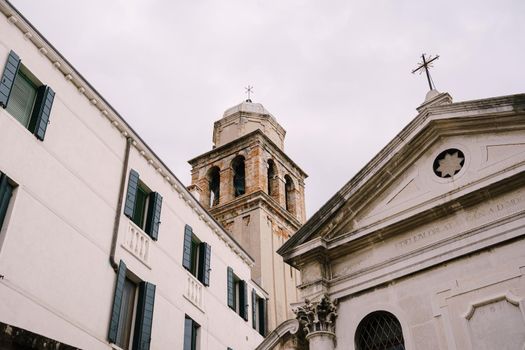 The brick tower of the bell tower towers over other buildings.