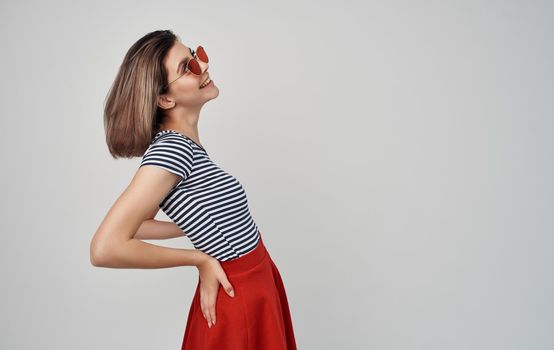 pretty woman in fashion clothes red skirt striped t-shirt sunglasses gesturing with hands. High quality photo