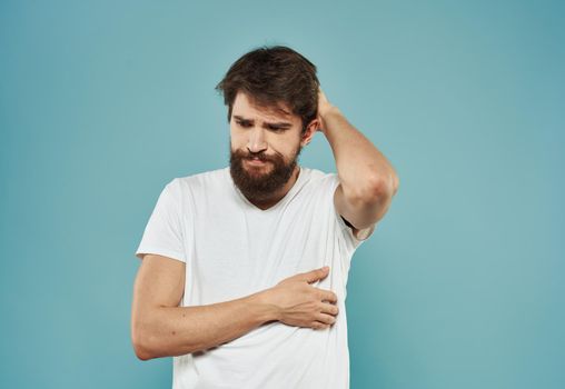 A brunette guy with a thick beard on a blue background gestures with his hands cropped view. High quality photo
