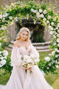 Portrait of the bride near the round arch of flowers. The scenery of the wedding ceremony. Wedding at an old winery villa in Tuscany, Italy.