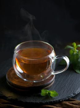 Teapot with tea surrounded with green leaves, tea ceremony, green tea in a transparent cup