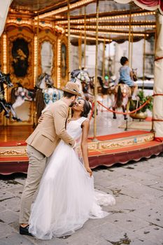 African-American bride and Caucasian groom near the carousel. Interracial wedding couple. Wedding in Florence, Italy