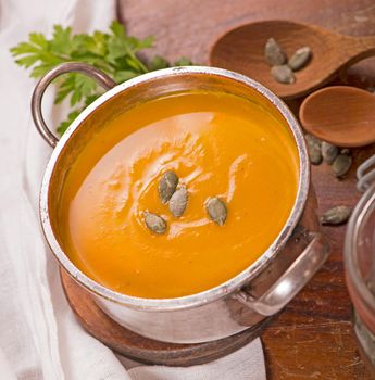 Bowl of pumpkin soup on rustic wooden background.