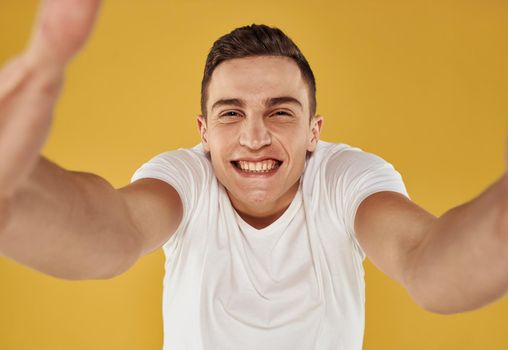 Portrait of a handsome guy in a white t-shirt on a yellow background cropped view. High quality photo