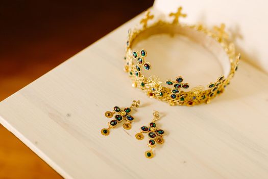 Golden crown with wedding crosses and gold earrings encrusted with precious stones