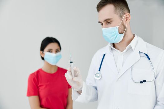 male doctor holding an injection next to a female patient. High quality photo