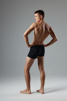 sporty man with pumped up body black shorts back view isolated background. High quality photo