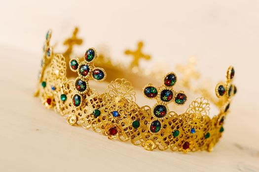 Golden crown encrusted with precious stones and crosses against a white background