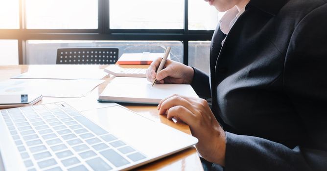 A woman hand holding a pen note some data on notepad for financial calculating.