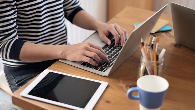 Close up young casual man sitting at desk studying on laptop happy at the coffee shop.