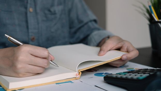 A woman using note some data on notepad for financial calculating.