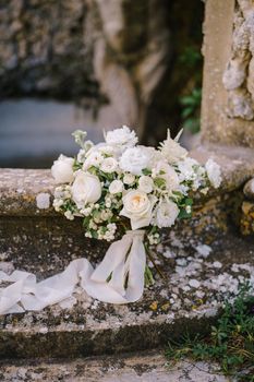 White bride bouquet on an old fountain.