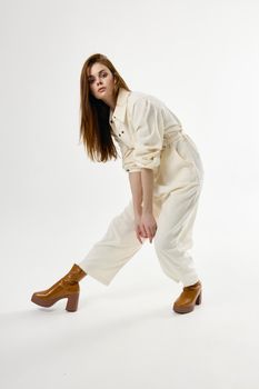 pretty woman in white jumpsuit leaned forward brown boots. High quality photo