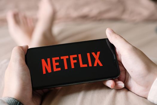 CHIANG MAI,THAILAND - APR 06, 2020 : Woman using iPhone X open Netflix application at home. Netflix is a global provider of streaming movies and TV series.