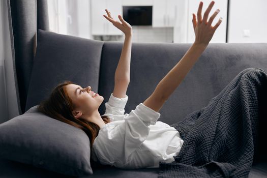 happy woman gesturing with her hands while lying on the sofa. High quality photo