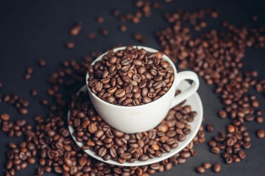coffee beans In a saucer and in a cup of coffee on a gray background female hand macro photography. High quality photo