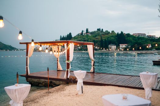 Wedding party on the beach near the gazebo decorated with garlands