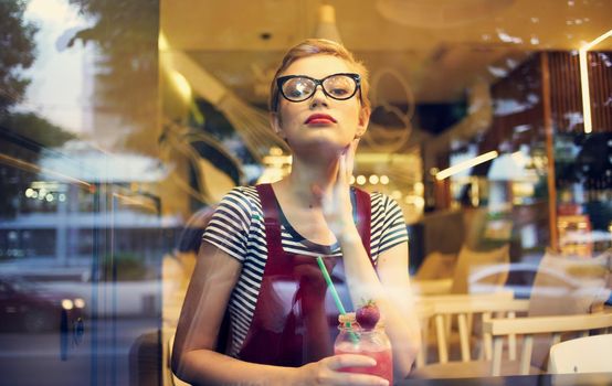 fashionable woman in red sundress resting in a cafe with a drink in her hand. High quality photo