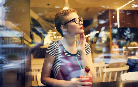 fashionable woman in red sundress resting in a cafe with a drink in her hand. High quality photo