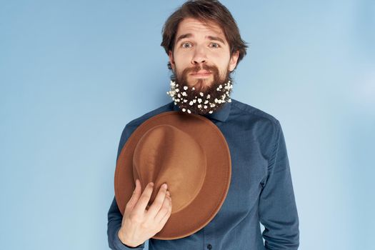 man in shirt flowers in beard hat emotions elegant style blue background. High quality photo