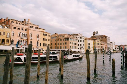 Tourists on the waterfront in Venice, against the background of the ancient facades of buildings standing in water. Water sightseeing in Venice, Italy.