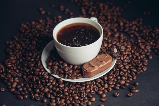 a cup of coffee and a chocolate bar on a saucer arabica beans variety drink. High quality photo