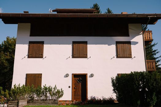 White whitewashed house, with wooden elements in northern Italy, in the Dolomites area, in a winter ski resort, in the city of Cortina Ampezzo.