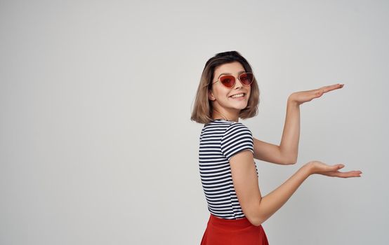 pretty woman in fashion clothes red skirt striped t-shirt sunglasses gesturing with hands. High quality photo