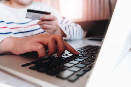 Close up hands holding credit card, typing on the keyboard of laptop, online shopping concept.