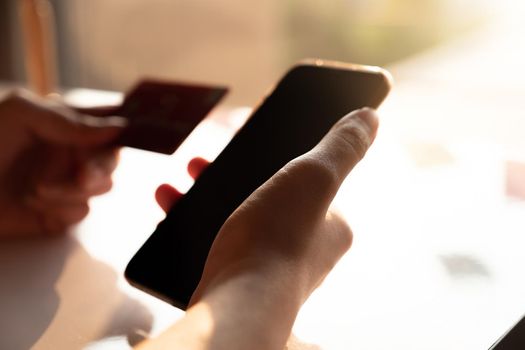 Online payment, Man's hands holding a credit card and using smart phone for online shopping at home