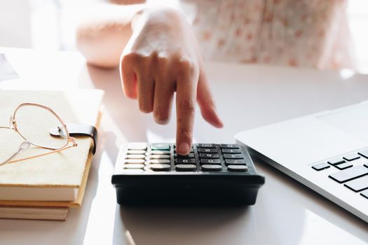 Close up Businesswoman using calculator and laptop for do math finance on wooden desk in office and business working background, tax, accounting, statistics and analytic research concept