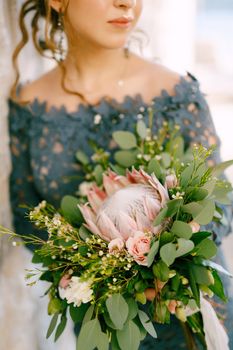 The bride in a stylish blue dress with wedding bouquet in the old town of Perast, close-up. High quality photo