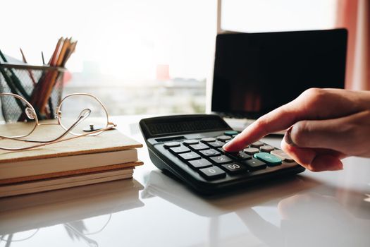 Close up Businesswoman using calculator and laptop for do math finance on wooden desk in office and business working background, tax, accounting, statistics and analytic research concept