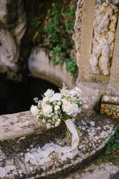 White bride bouquet on an old fountain.