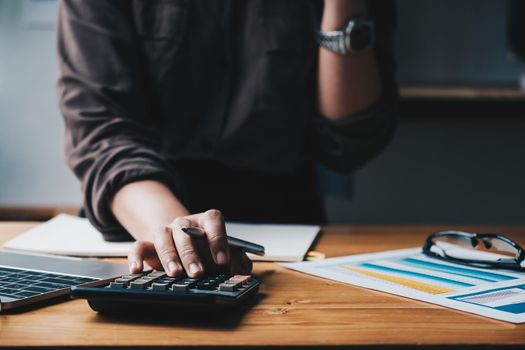 Business woman entrepreneur using a calculator with a pen in her hand, calculating financial expense.