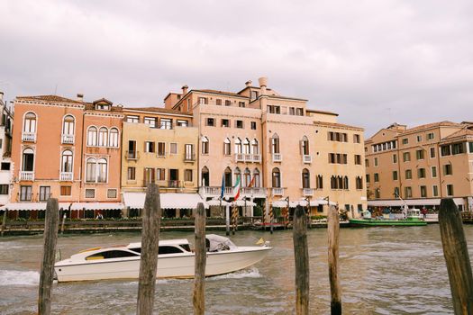 Tourists on the waterfront in Venice, against the background of the ancient facades of buildings standing in water. Water sightseeing in Venice, Italy.