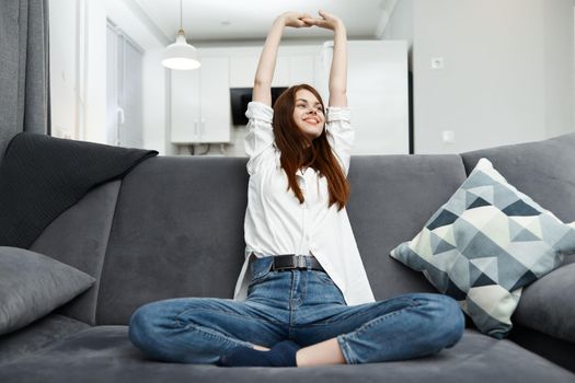 cheerful woman holding her hands above her head Sitting on the sofa comfortably sitting in the apartment. High quality photo