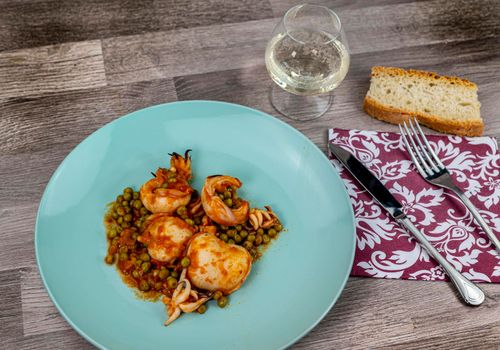 flat composition cuttlefish and peas with glass of wine cutlery and bread